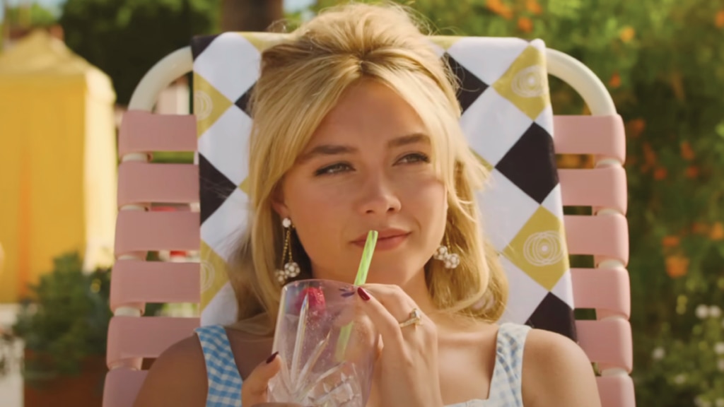 Florence Pugh on the set of 'Don't Worry, Darling,' sitting on a lawn chair and sipping at a drink.