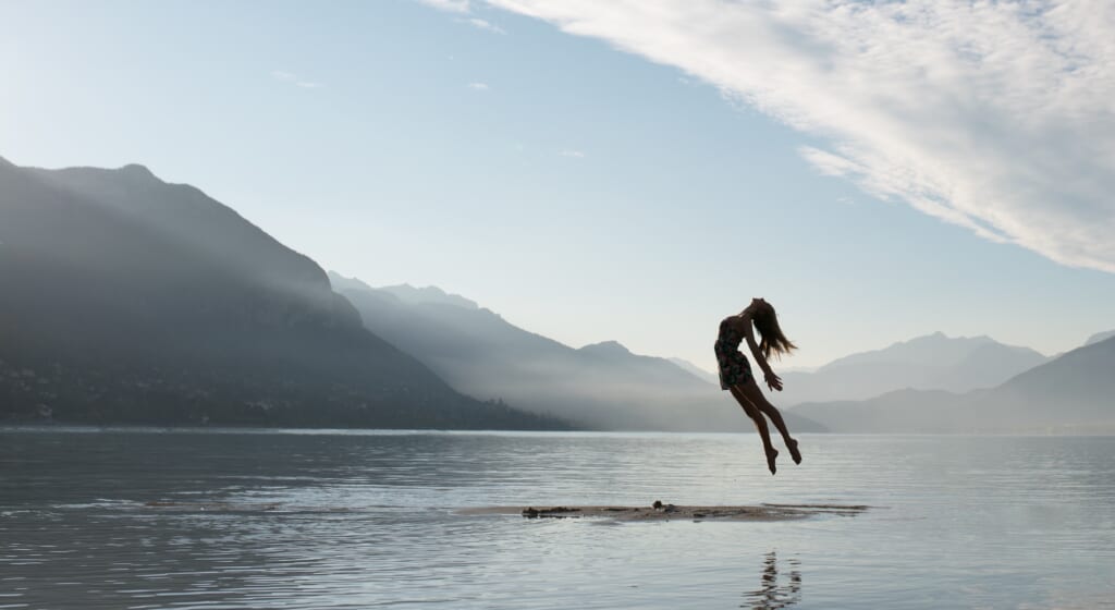 floating person above water surrounded by mountains
