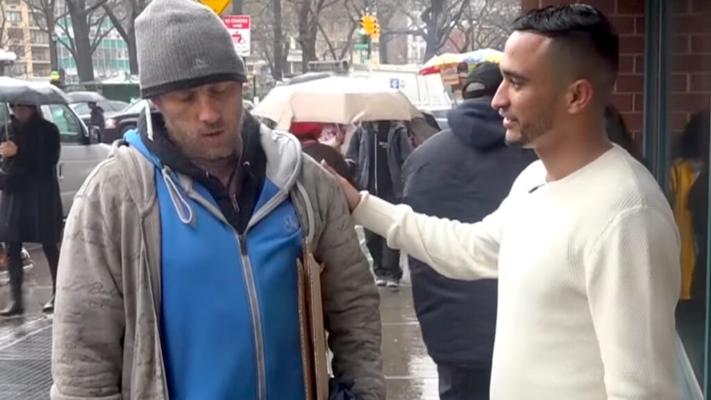 Waqas Shah assures a sad homeless man in a blue hoodie on a busy NYC street